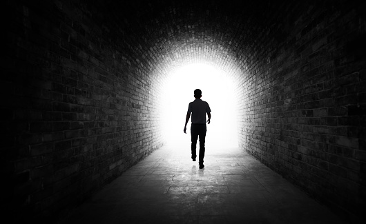 Young man walking through a dark tunnel