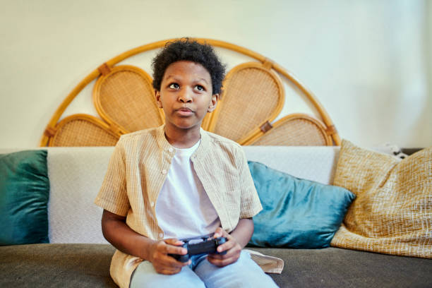 istock Focus, sofa and child playing video games for fun, weekend activity and online competition. Looking, console and a boy kid on the living room couch for gaming, home entertainment and technology game 1487305152