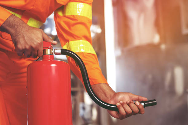 istock hand presses the trigger fire extinguisher available in fire emergencies conflagration damage background. Safety 1487307533