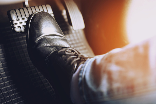 man stepping on car brake To slow down, stop the car both normal and abruptly, transfer the weight to press the front wheels to grip the road and turn more stable