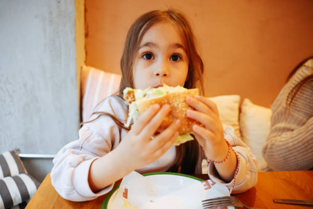 istock A little girl eats fast food in a cafe 1487309411