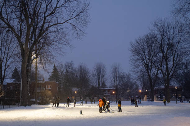 Group of people are playing hockey in a public park in Ahuntsic, Montreal.