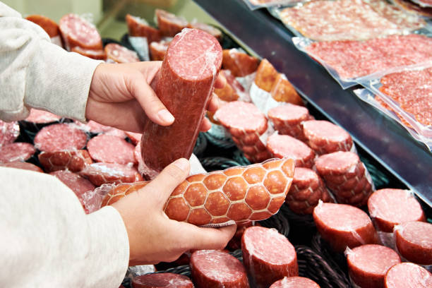 istock Sliced sausage in hands in store 1487313608