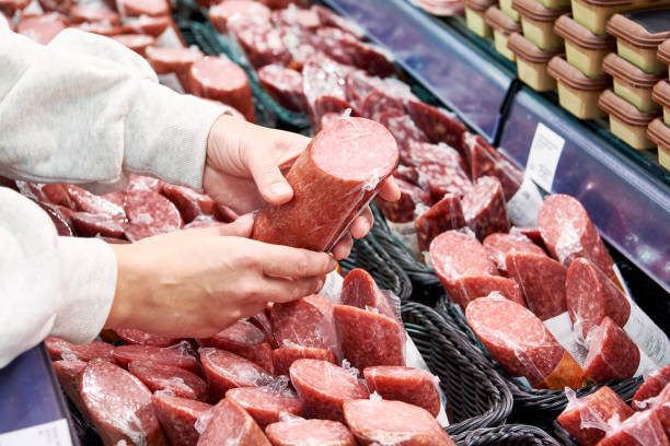 istock Sliced sausage in hands in store 1487313661
