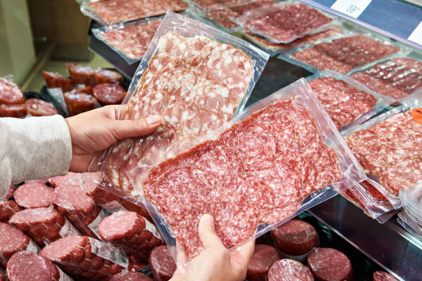 istock Sliced sausage in plastic pack in hands in store 1487313707