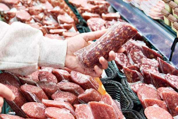 istock Sliced sausage in hands in store 1487313739
