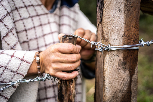 Close-up of a man opening or closing barbed wire gate