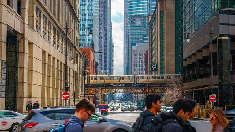 Time lapse of Crowd pedestrian and tourist walking and crossing intersection at Railroad bridge with traffic among modern buildings of Downtown Chicago, Illinois, United States