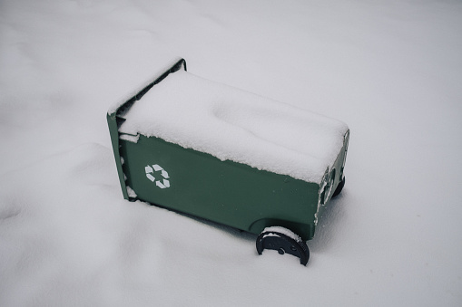 A green recycling bin buried in snow in Montreal.