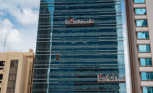 Beautiful view of the skyscrapers of Abu Dhabi . workers washing windows on a high skyscraper in the city