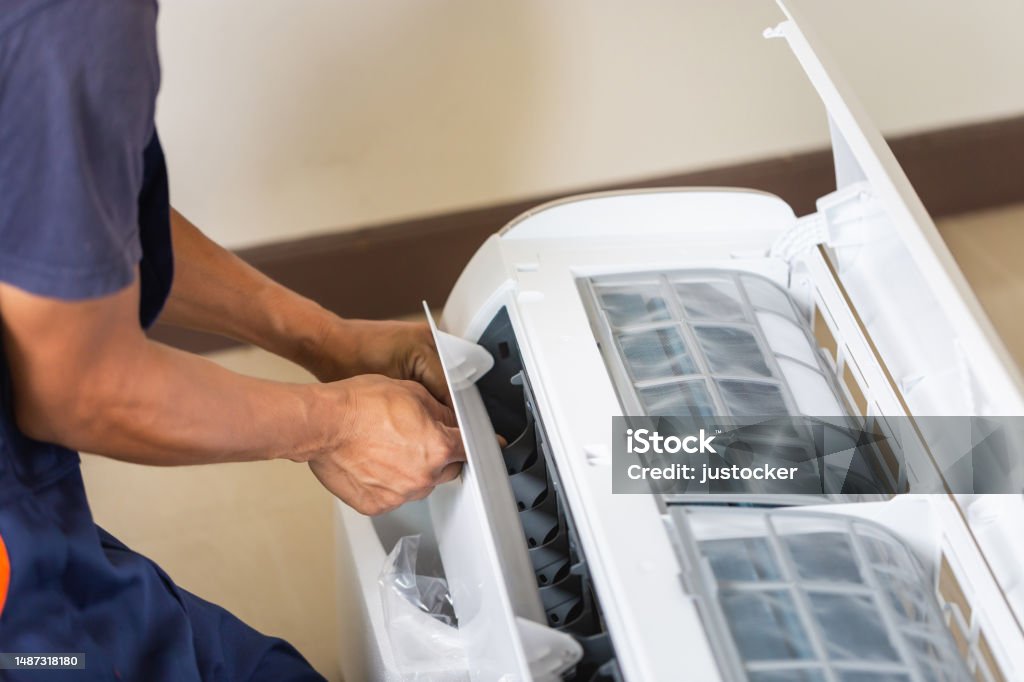 Technician man installing an air conditioning in a client house, Young repairman fixing air conditioner unit, Maintenance and repairing concepts Air Conditioner Stock Photo