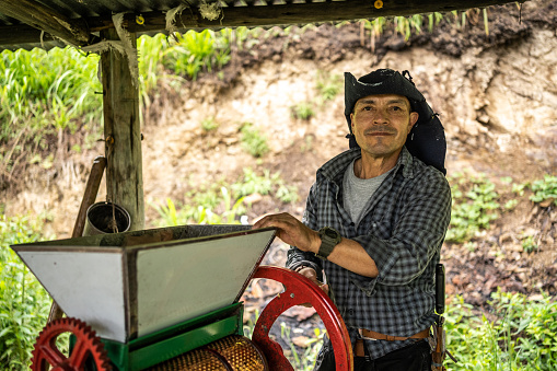 Portrait of a mature farmer using machine for grain washing and fermentation in the agricultural field