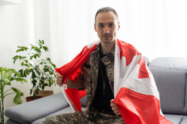 istock man in military uniform holding canada national flag while. 1487320188