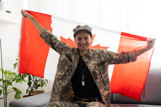istock man in military uniform holding canada national flag while. 1487320235
