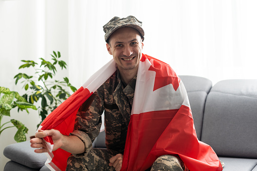 man in military uniform holding canada national flag while
