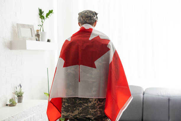istock man in military uniform holding canada national flag while. 1487320787