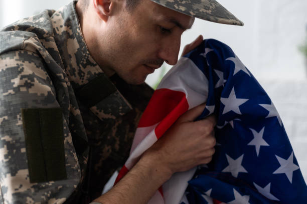 istock soldier in uniform and cap holding american flag 1487321177