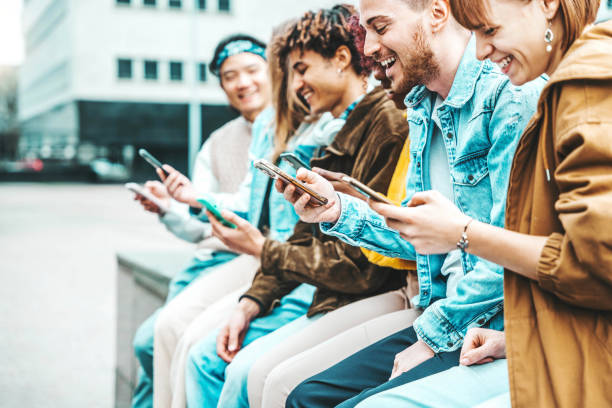 istock Happy group of multiracial teens using smart mobile phone outdoors - Diverse university students watching smartphones in college campus - Millenial people having fun on city street - Youth culture 1487322161