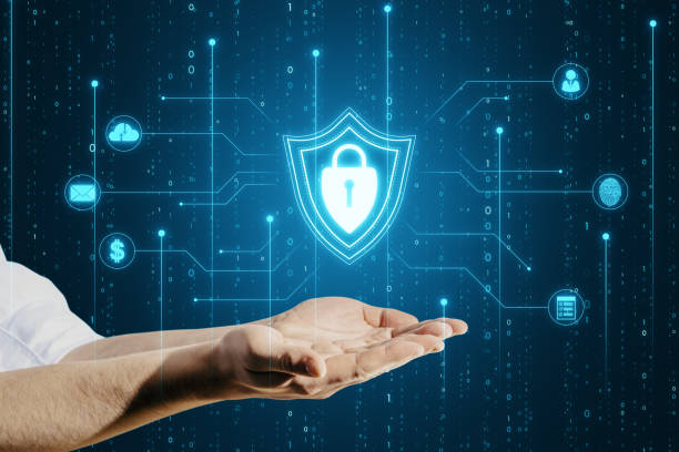 istock Close up of male hands holding glowing blue padlock shield with digital coding on dark background. Safety, programming and access concept. 1487323873