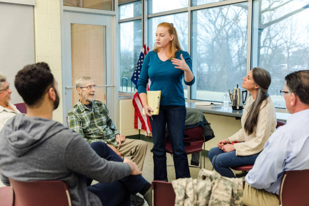 istock Female counselor gestures while introducing herself to the group of veterans 1487326394