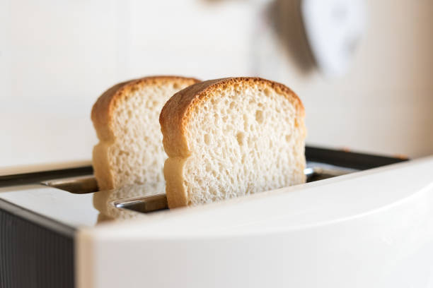 istock 2 white fresh slices of bread in a white toaster, selective soft focus 1487328294
