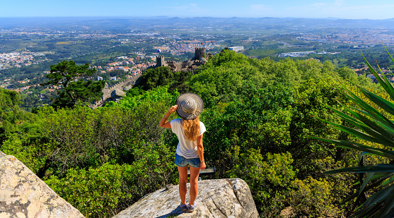 Woman tourist standing looking at panoramic view of Moorish castle in Sintra- Portugal