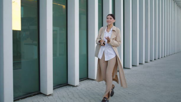 istock Walking girl talking mobile by wireless earbuds. Lady going work speaking phone 1487329933