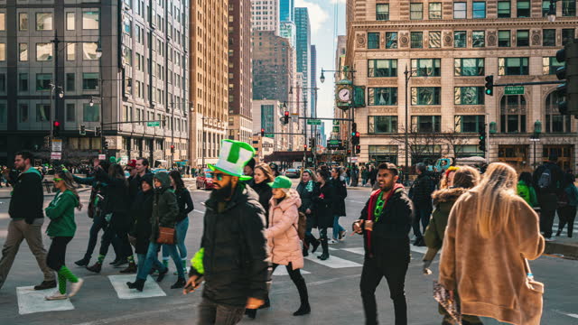 Time lapse of Crowd pedestrian and tourist walking and crossing intersection crosswalk with traffic jam among modern buildings of Downtown Chicago in St. Patrick's Day, Illinois, United States