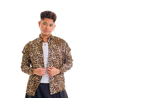 portrait of non-binary young asian person wearing leopard print shirt standing looking straight at camera on pure white background