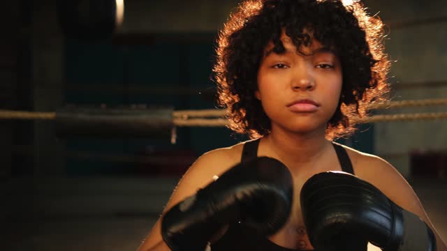 Outcry independent girl power. Angry african american woman fighter with boxing gloves looking serious aggressive to camera standing on boxing ring. Strong powerful girl looking concentrated straight.