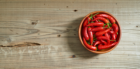 Wooden plate with hot chili peppers. On a rustic dark background. High quality photo