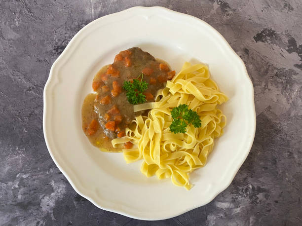 Austrian beef schnitzel with mustard in carrot, tomato paste, sour cream gravy. Served with Tagliatelle Pasta.