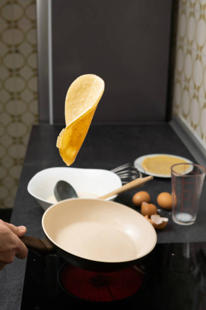 Pancake flipping in the air over frying pan with all ingredients on bottom