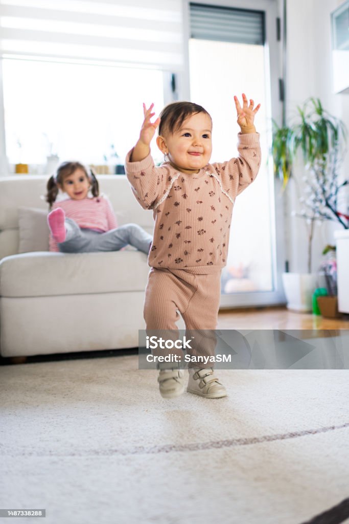 She is walking! Cousin supporting first steps of baby girl. 12-23 Months Stock Photo