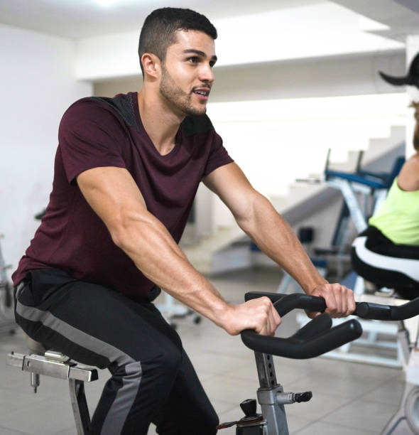 Fit young man having sports training on exercise bike in a gym