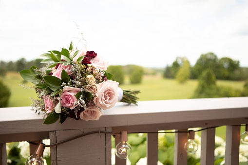 An artfully arranged bouquet of colorful flowers sits atop the railing of a quaint home
