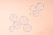 Drops and smears of cosmetics. Drops of liquid transparent gel with bubbles on a beige background