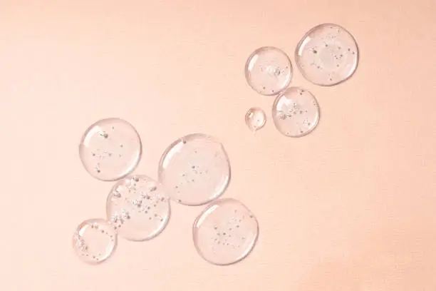 Photo of Drops and smears of cosmetics. Drops of liquid transparent gel with bubbles on a beige background