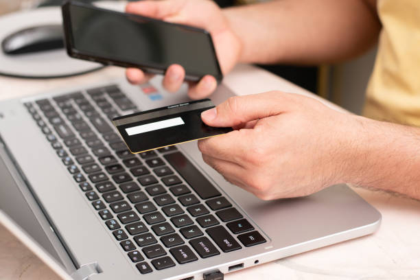 istock Person using credit card front their laptop while hold a cell phone, buying in web online. 1487349726