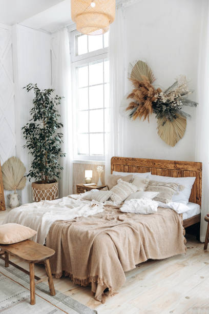 istock Cozy rustic bedroom with boho ethnic decor. Large windows. Double wooden bed with many pillows and handmade textiles. Wooden furniture. Plants in the interior. Nobody. Large windows in appartment 1487350983