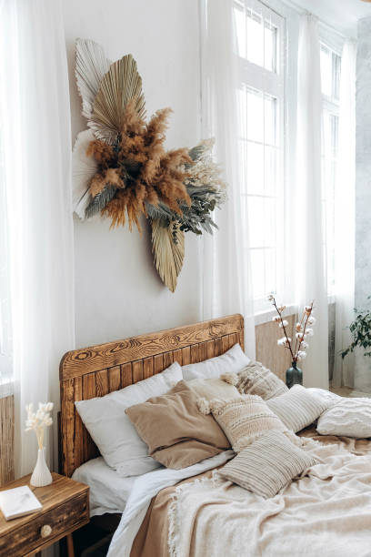 istock Cozy rustic bedroom with boho ethnic decor. Large windows. Double wooden bed with many pillows and handmade textiles. Wooden furniture. Nobody. Large windows in appartment 1487351062