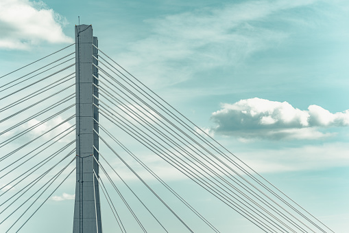 Close up detail with a cable stayed suspension bridge against the blue sky.