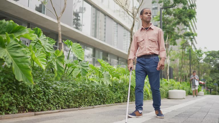 Blind man walking in the street with his walking cane