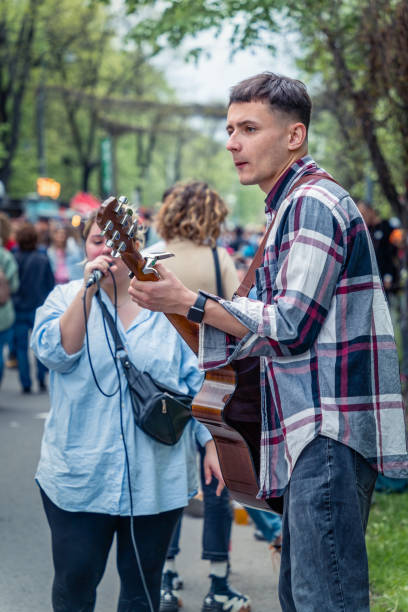 jeune artiste de rue avec une guitare acoustique jouant dans le centre de bucarest (rue de la victoire - calea victoriei). - romania men artist portrait photos et images de collection