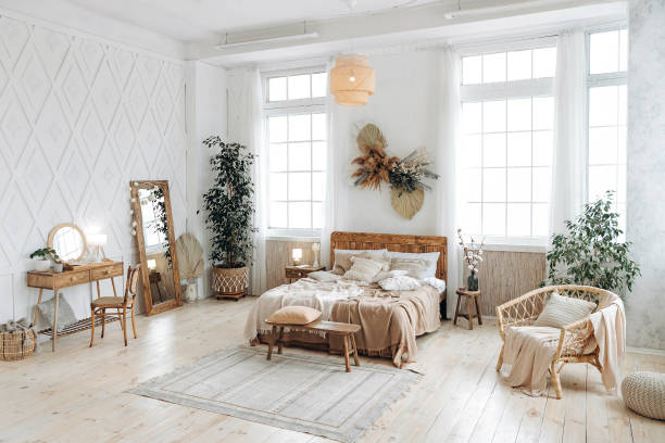istock Cozy rustic bedroom with boho ethnic decor. Bright spacious apartment with large windows. Nobody. Wooden furniture. Boudoir table. Large mirror. Handmade textile. Plants in the interior 1487352474