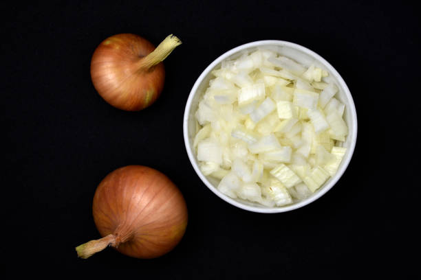 Two bulbs on a black background. Vegetables close-up. Fresh chopped onion.