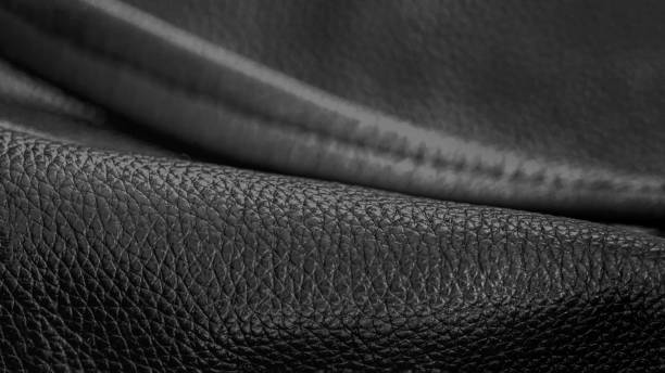 istock Rolled up black leather close up, abstract background, texture. Commercial and industrial concept. Selective focus 1487356414