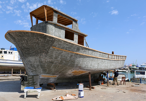 Karatas, Adana, Turkey-August 29,2022: Unidentified Man fixing the Old Boat at Shipyard