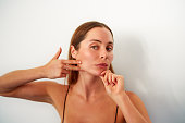 portrait young caucasian woman practicing facial yoga exercises in studio