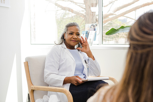 The mature female counselor sits in her chair to listen to the unrecognizeable patient discuss challenges she has been facing.